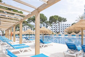 Un espace aménagé au bord de la piscine, avec des chaises longues, des parasols et une vue dégagée sur la piscine.