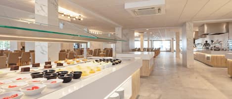 Een modern restaurant in een hotel met een buffet, marmeren zuilen en een ruime opzet.