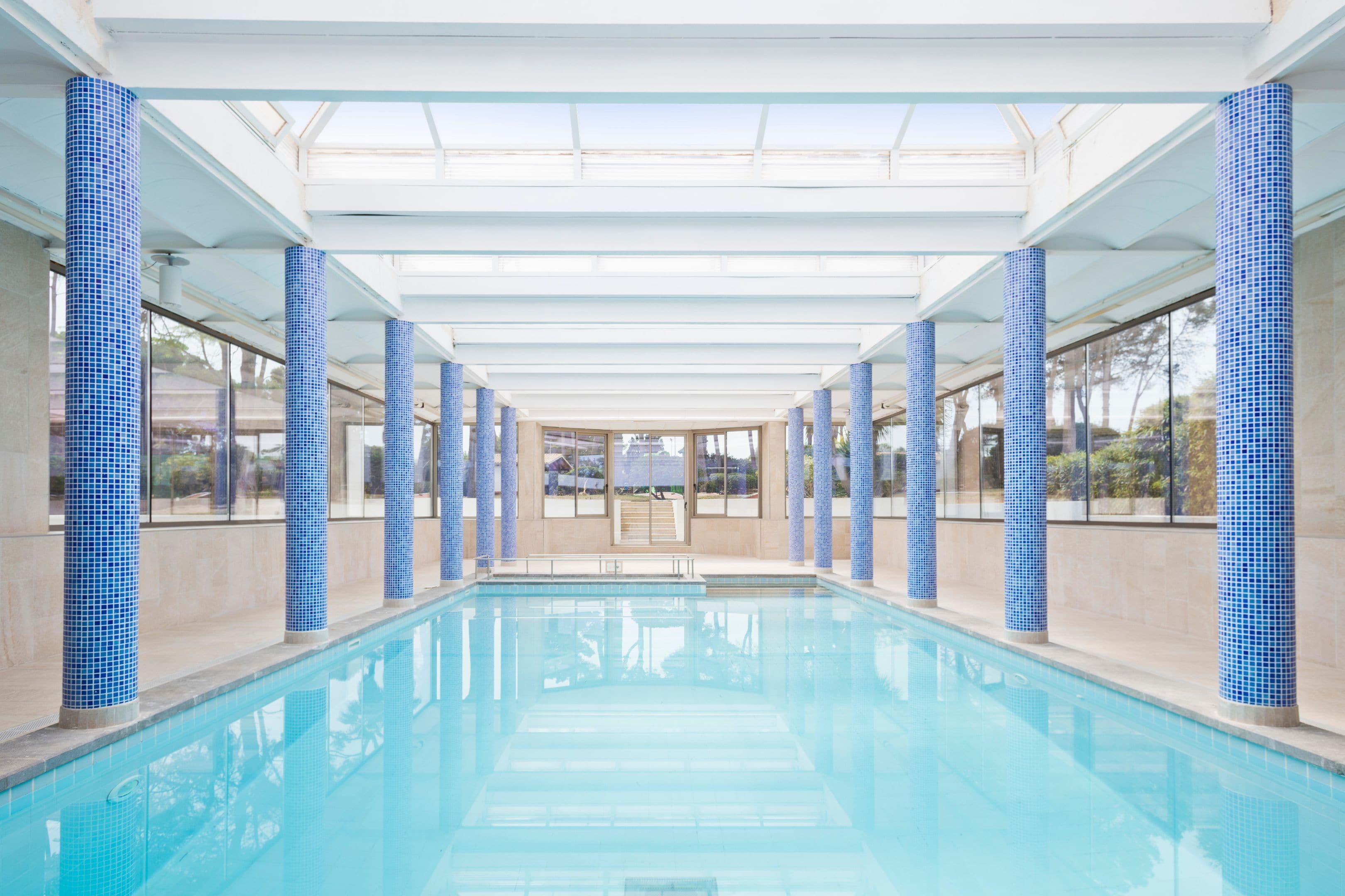 Una piscina cubierta, una piscina al aire libre, sombrillas, tumbonas