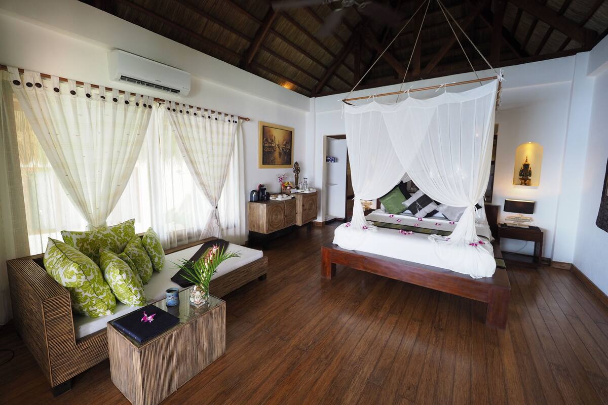 A room with a bed, a sofa, a small table, and a bedside table.