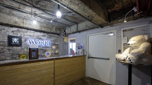 A reception area with a wooden counter, a neon sign reading "WORK", and a large teddy bear on a stand. - Work Inn TPE - Hostel (Taipei)