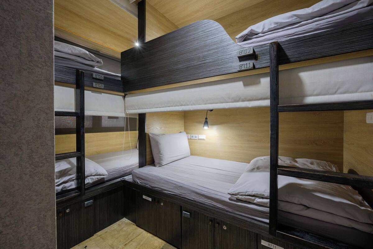 A bunk bed room with wooden walls and a small desk area.