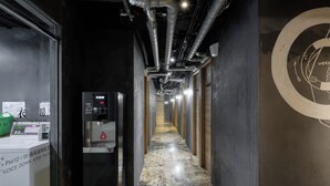 A hallway with a vending machine, a water dispenser, and a sign indicating voice down after PM10. - Work Inn TPE - Hostel (Taipei)