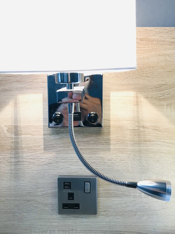Une prise de courant murale dotée d’un port USB et d’une prise électrique standard, reliée à un câble d’extension métallique.