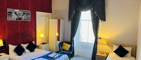 Habitación de hotel con dos camas, un espejo, un armario y una ventana con cortinas.