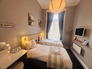 A hotel room with two beds, a television, and a sign that reads 'OUR HAPPY PLACE'. - Ardenlee Guest House (Edinburgh)