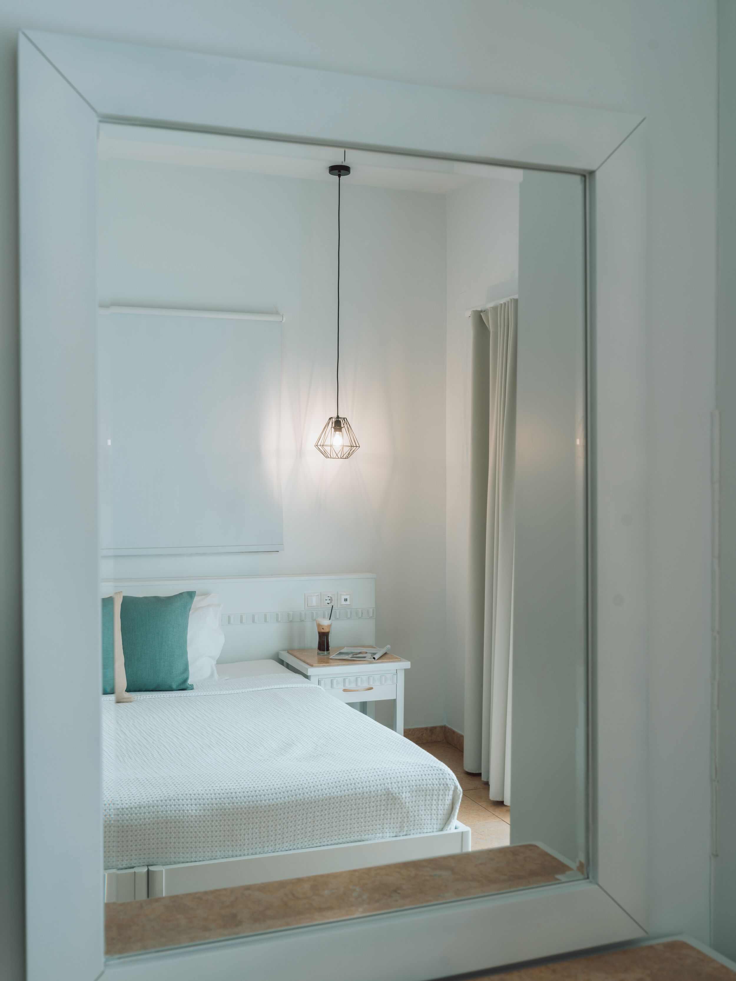 A modern bedroom with a bed, bedside table, and a hanging light fixture.