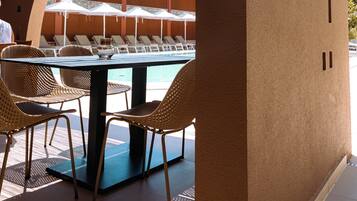 Un espace aménagé au bord de la piscine, avec des chaises longues, une table et un coin salon abrité.