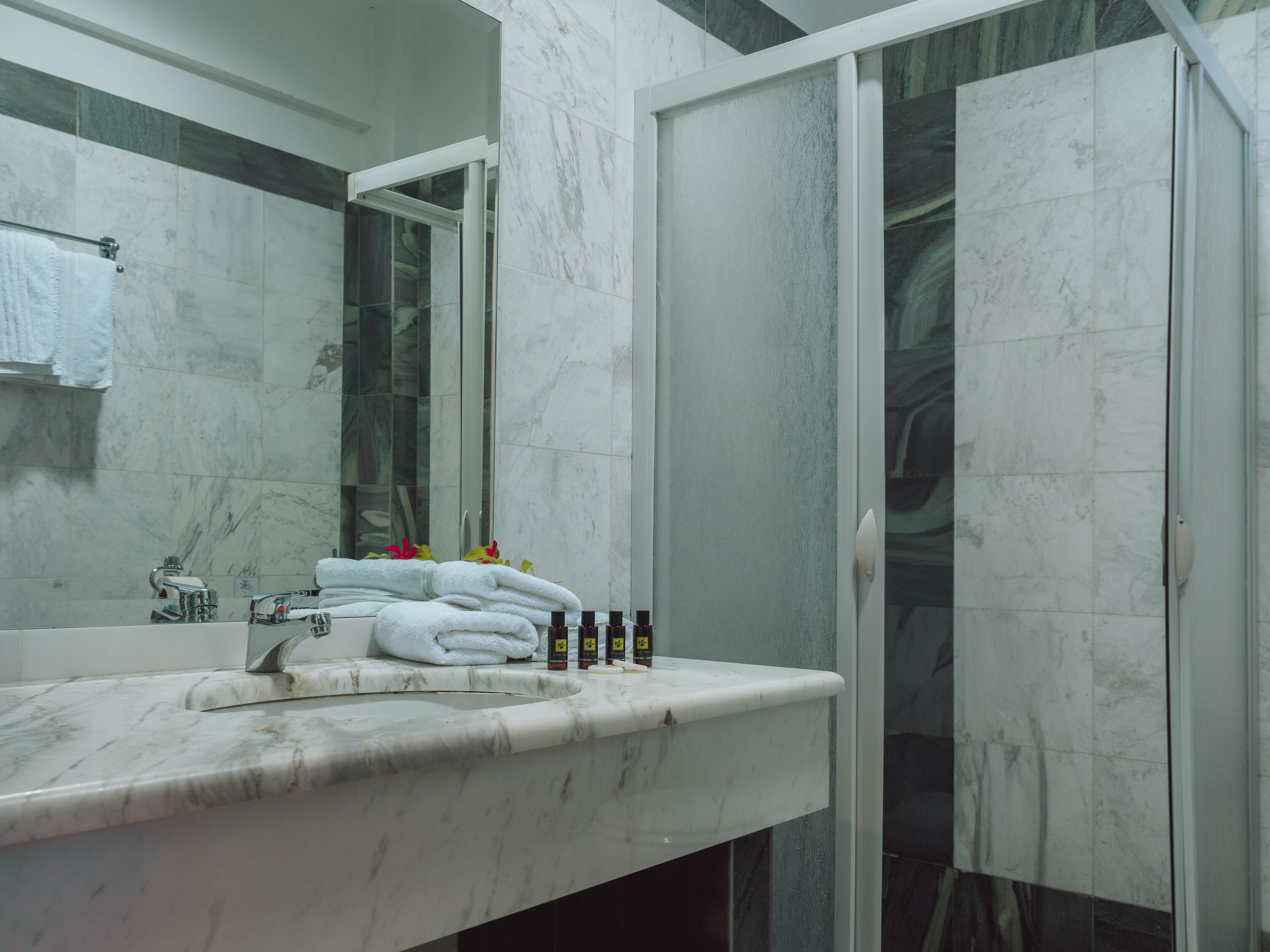 A modern bathroom with a marble sink, a glass shower enclosure, and a towel rack.