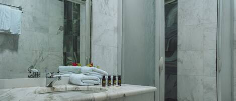 A modern bathroom with a marble sink, a glass shower enclosure, and a towel rack.