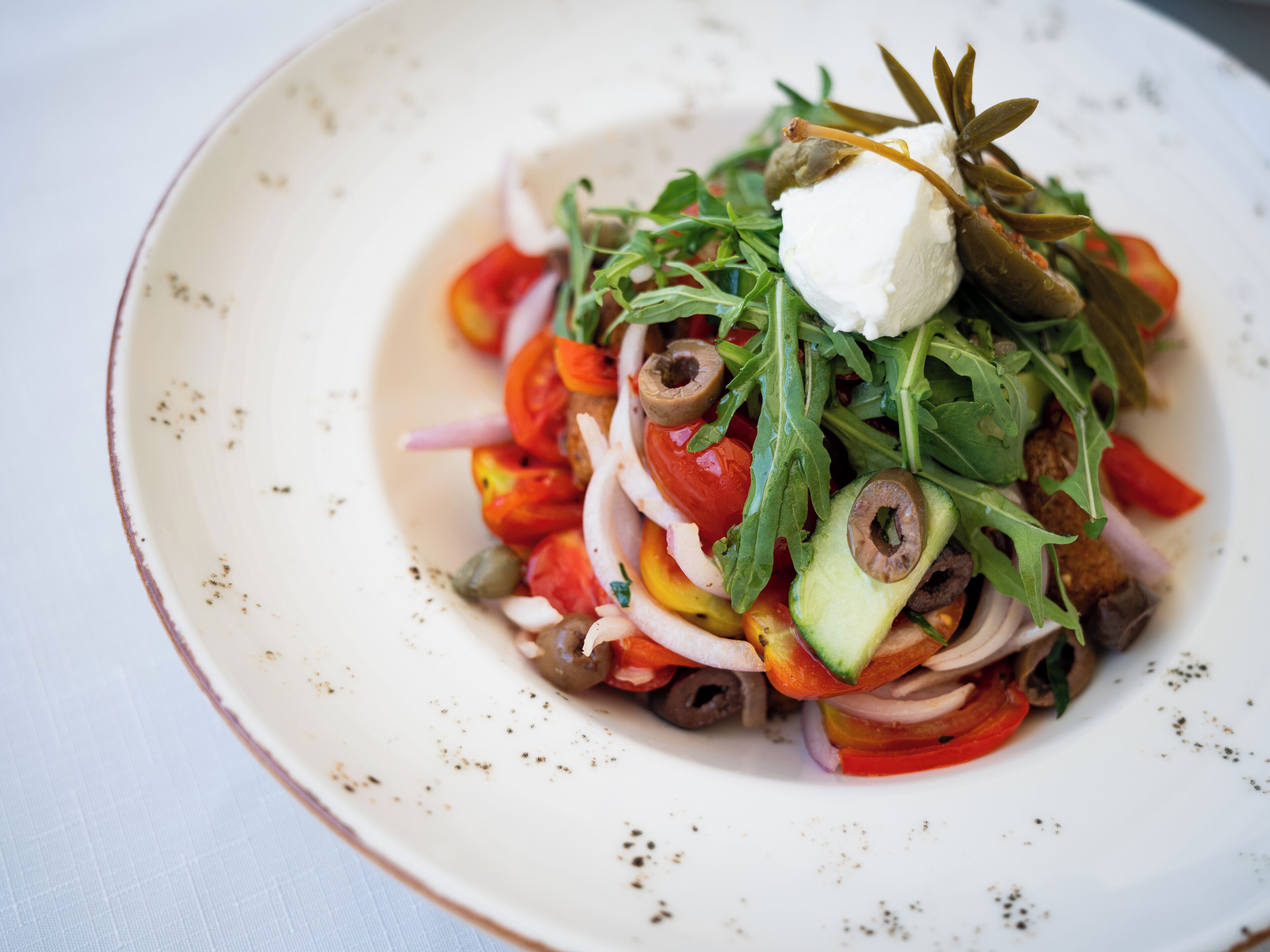 A plate of food with various vegetables and a dollop of cream on top.