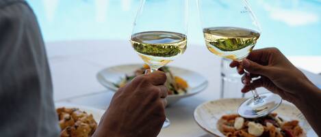 Two people toasting with wine glasses at a table with plates of food.