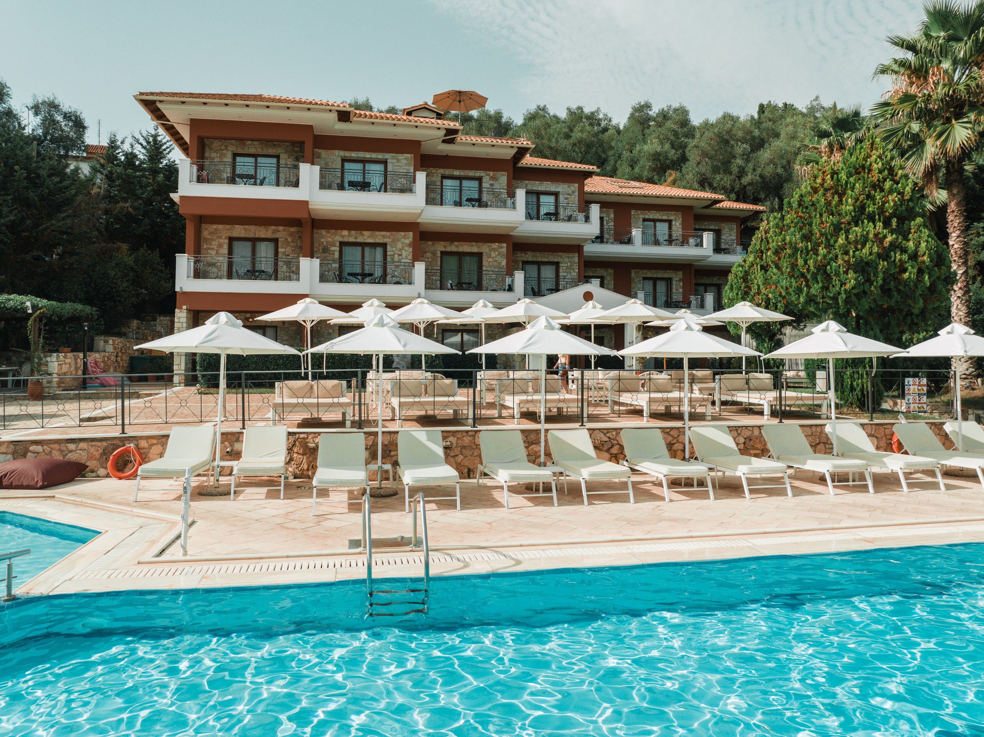 A hotel with a swimming pool, sun loungers, and umbrellas.