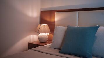 A neatly made bed with a headboard, a bedside lamp, and two pillows.
