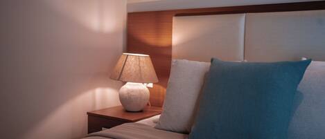 A neatly made bed with a headboard, a bedside lamp, and two pillows.