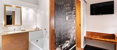 A modern bathroom with a white sink, wooden vanity, a bathtub, and a large mirror.