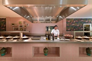 Una cocina moderna con baldosas rosas, electrodomésticos de acero inoxidable y jarrones decorativos.