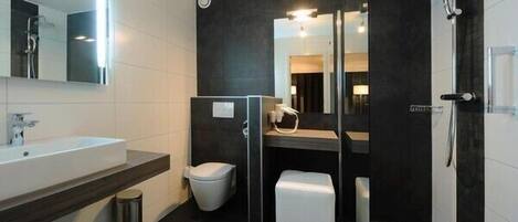 A modern bathroom with a large sink, toilet, and shower area.