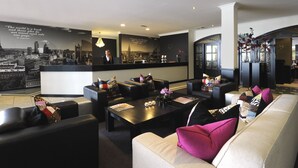 A modern hotel lobby with a reception desk, seating area, and decorative elements. - Van der Valk Hotel Nazareth - Gent (Nazareth)