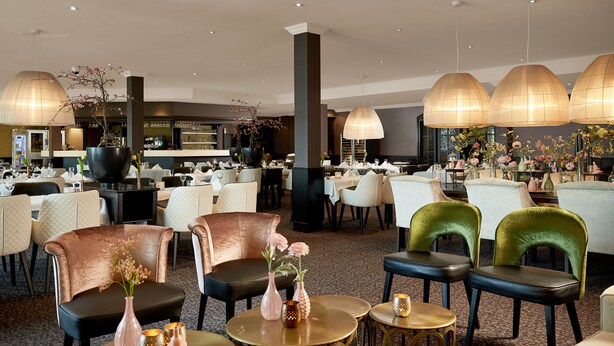A spacious hotel lobby with multiple seating areas, a bar, and a large chandelier. - Van der Valk Hotel Nazareth - Gent (Nazareth)