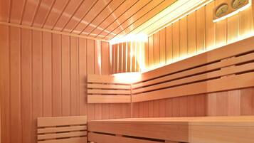 Een sauna met houten banken en een bank met handdoeken en een mand.
