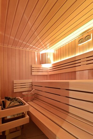 Una sauna con bancos de madera y un banco con toallas y una cesta.