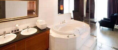 A modern bathroom with two sinks, a large bathtub, and a glass shower enclosure.