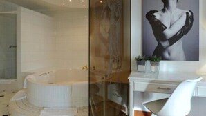 A modern bathroom with a large bathtub, a white vanity, and a mirror. - Van der Valk Hotel Nazareth - Gent (Nazareth)