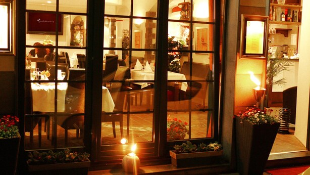 A restaurant with a glass partition, tables set for dining, and a warm interior lighting. - Hotel Altera Pars (Cologne)