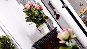 A white wall with a white vase containing pink roses. - Hotel Altera Pars (Cologne)