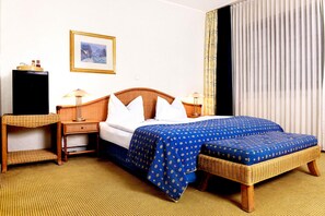 A hotel room with a bed, two bedside tables, a lamp, a picture on the wall, and a window with curtains. - Hotel Altera Pars (Cologne)
