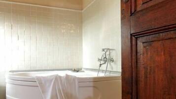 Bathroom features a bathtub and tiled floor and walls.