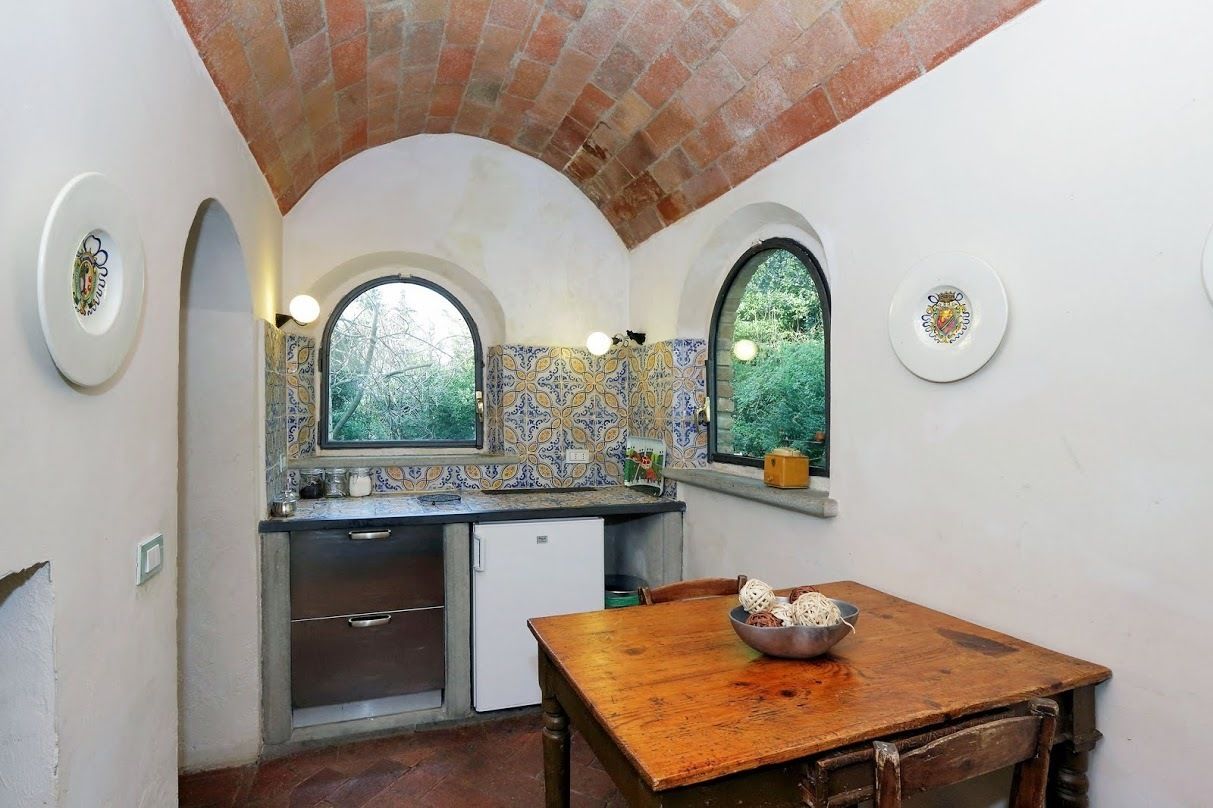 A compact kitchen with a wooden table, a built-in sink, and a window overlooking greenery.