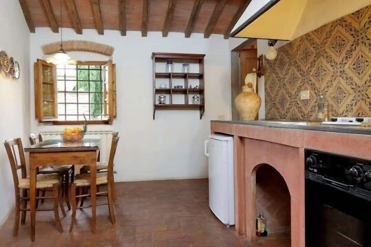 Une cuisine au décor rustique, avec des poutres apparentes, un sol en pierre et un poêle traditionnel.