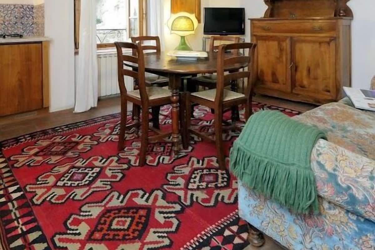 Une pièce chaleureuse avec un plafond en bois, une table à manger avec des chaises, un téléviseur, un meuble et un tapis à motifs.