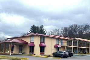 A motel with a two-story structure, a covered parking area, and a visible staircase to the upper level.