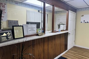Uma área de recepção com balcão de madeira, um quadro com o logotipo do Membro Empresarial do Xerife da Virgínia, um aviso indicando a disponibilidade de gelo no escritório e um mural de avisos.
