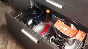 Eine Küche mit zwei Spülen, einer Arbeitsplatte mit verschiedenen Gegenständen und einer Schublade voller Küchenutensilien.
