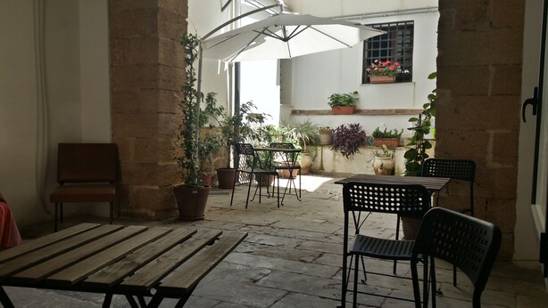 Eine Außenpatio-Terrasse mit Holzbänken und -stühlen, Blumentöpfen und einem Tisch.