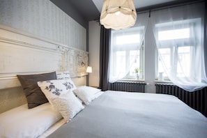 A neatly made bed with a white and grey duvet, a headboard with a decorative panel, and a bedside lamp. - Miss Sophie's New Town (Prague)