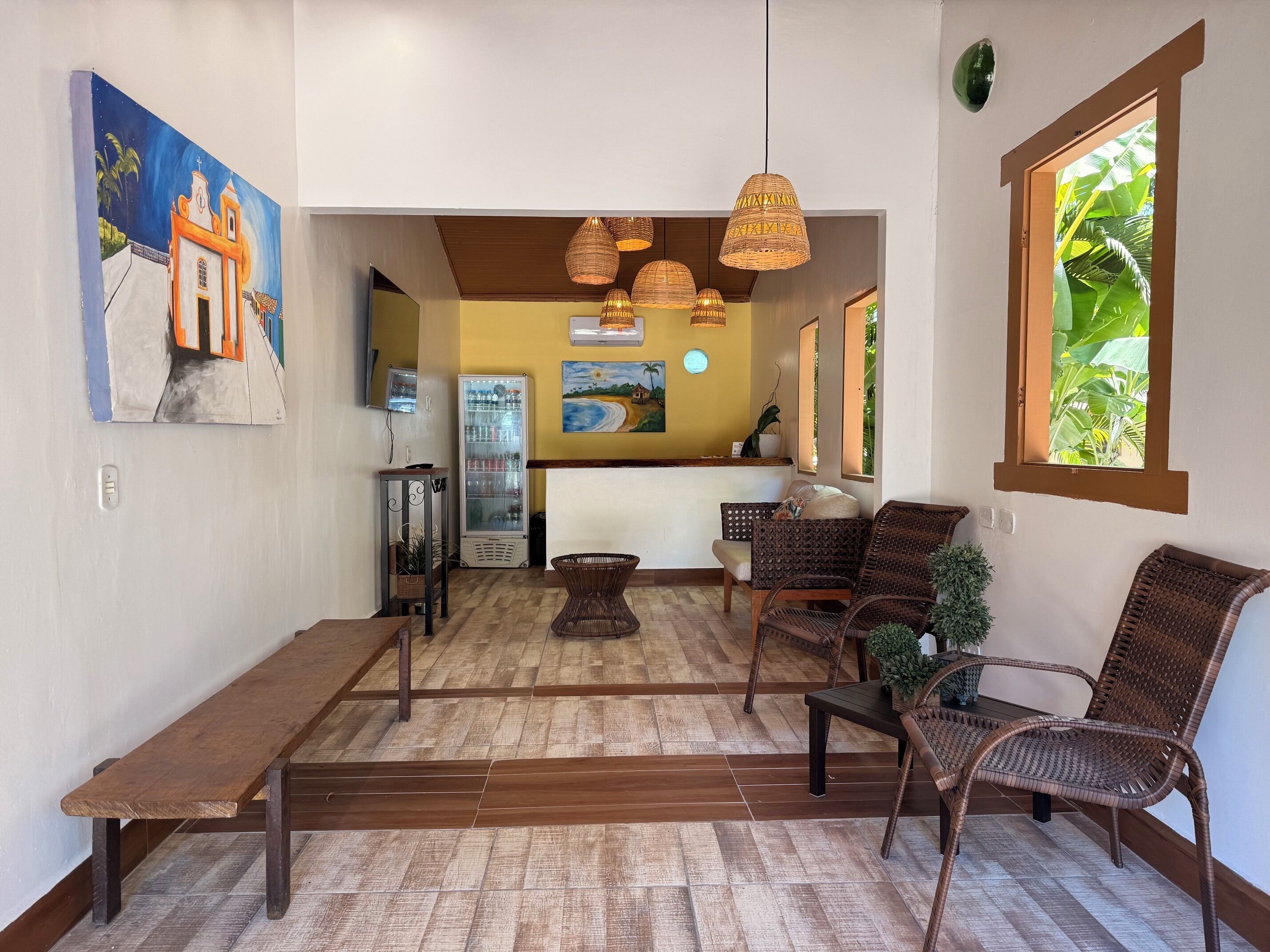 A reception area with wicker furniture, a refrigerator, and artwork on the walls.