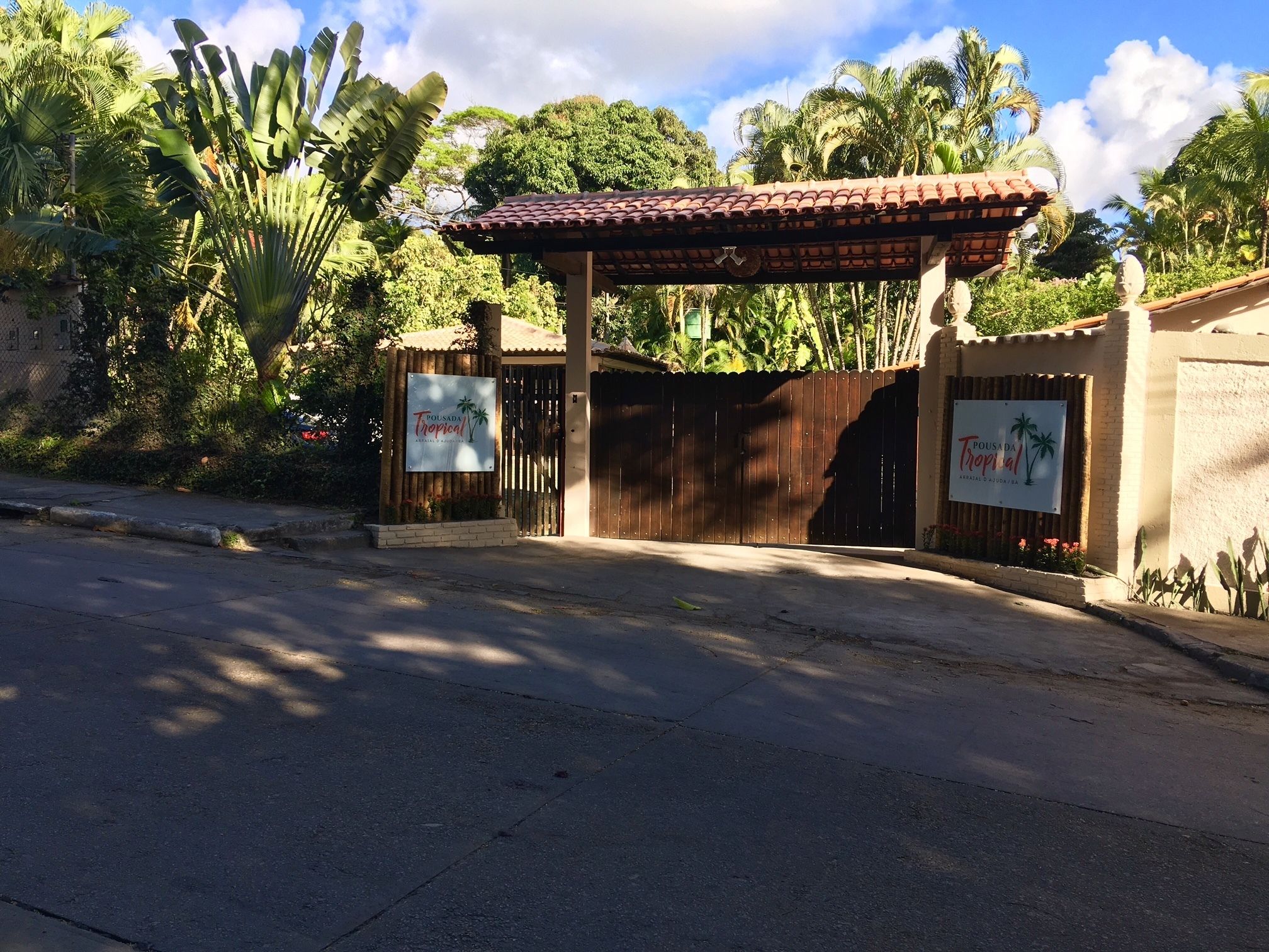 Une entrée fermée par un portail mène à une propriét é où un panneau indique « Pousada Tropical ».