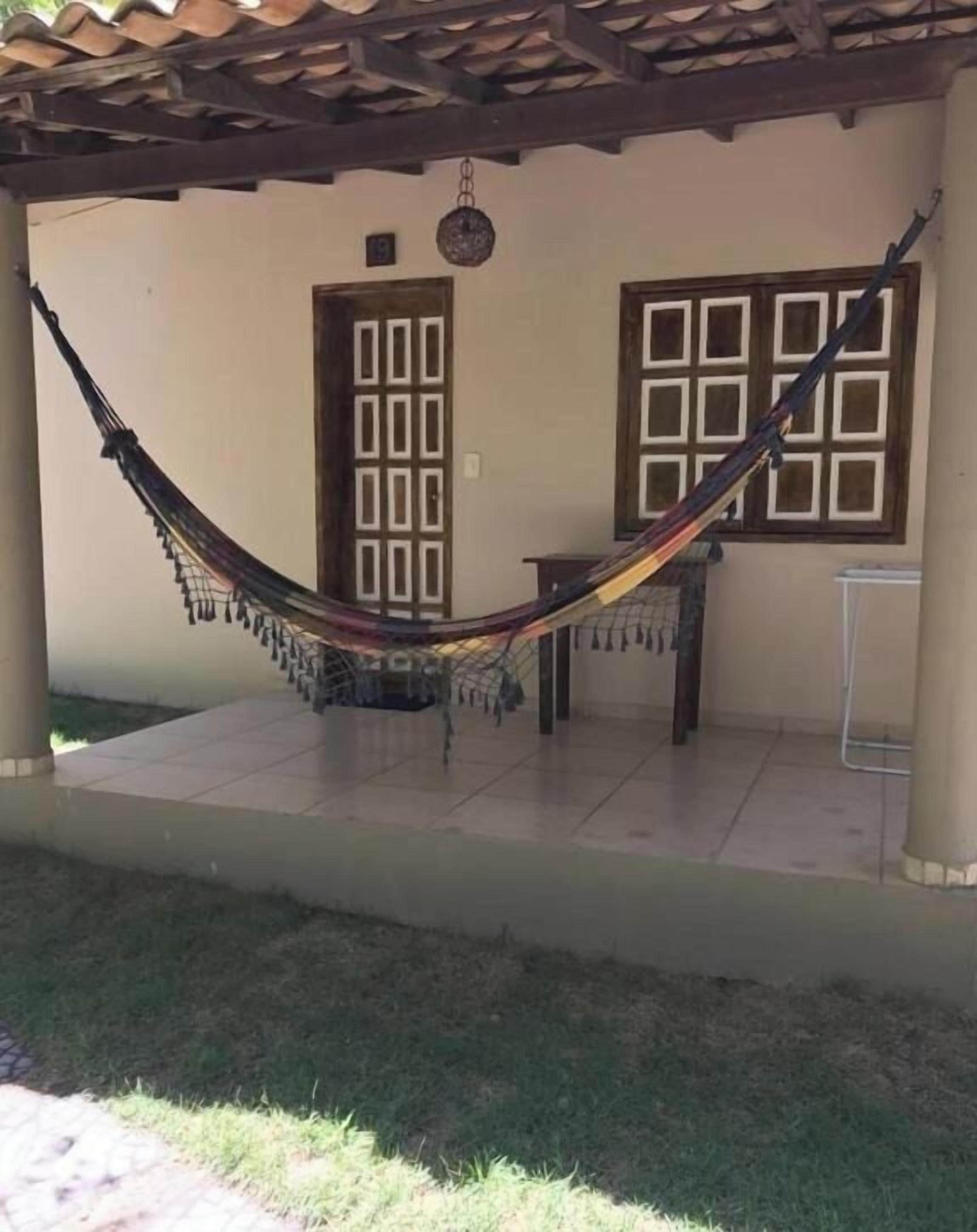 Une véranda couverte avec un hamac, une porte et une fenêtre.