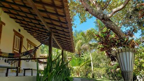 A covered outdoor area with a hammock, a pathway, and lush greenery. - Pousada Tropical Arraial (Porto Seguro)