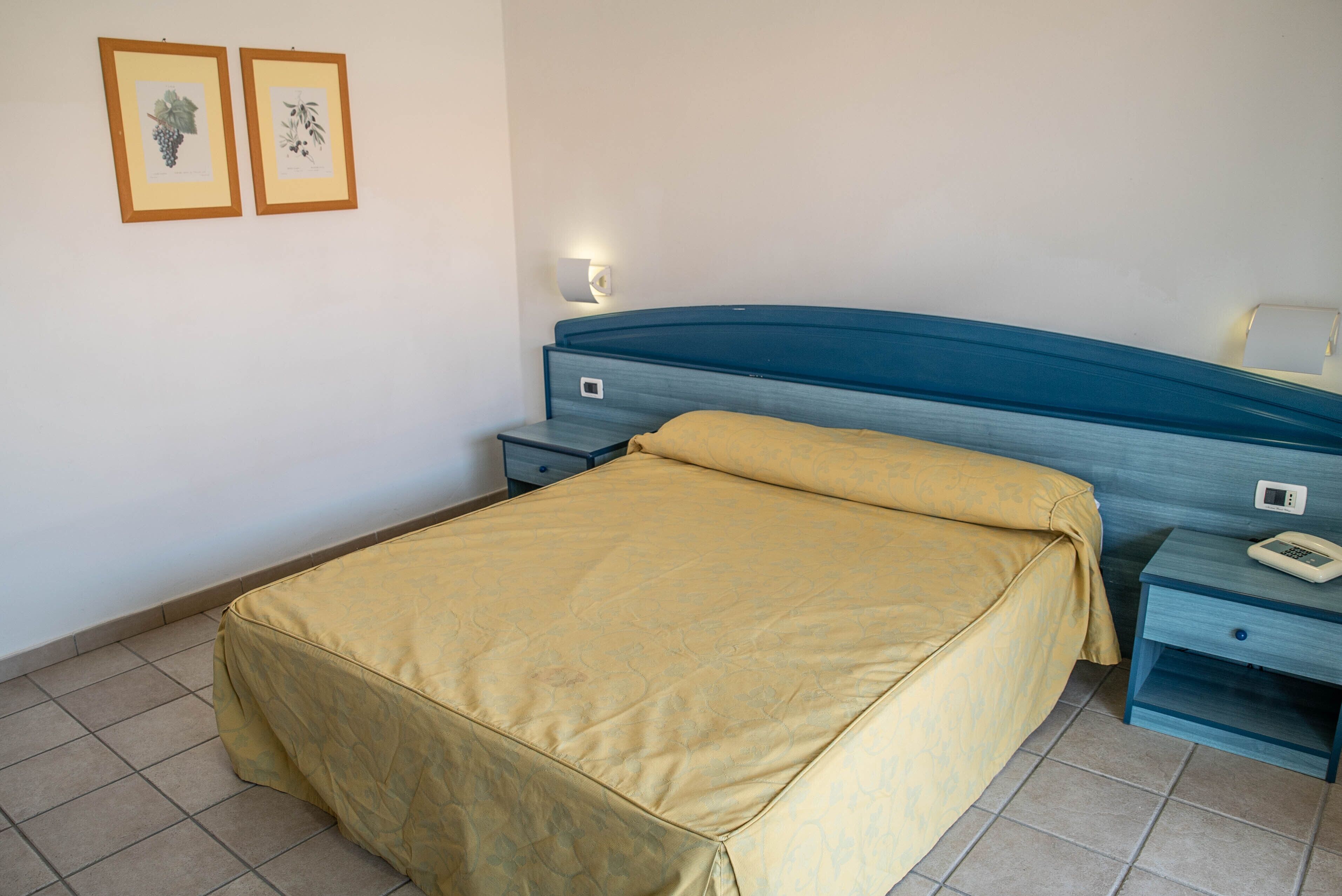 Una camera da letto con un letto, un comodino e una lampada a parete.