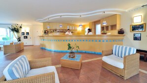 A reception area with a counter, wicker furniture, and potted plants. - Nicotera Beach Village (Nicotera Marina)