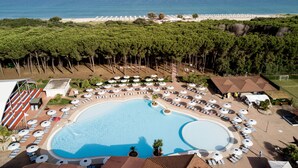 A resort with a large pool surrounded by sun loungers and umbrellas, a beach area with umbrellas, and a view of the sea. - Nicotera Beach Village (Nicotera Marina)