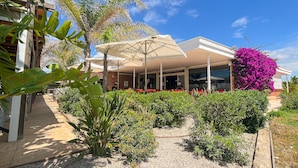A restaurant with outdoor seating, covered by umbrellas, surrounded by greenery and a clear sky. - Camping 3 Estrellas (Gava)