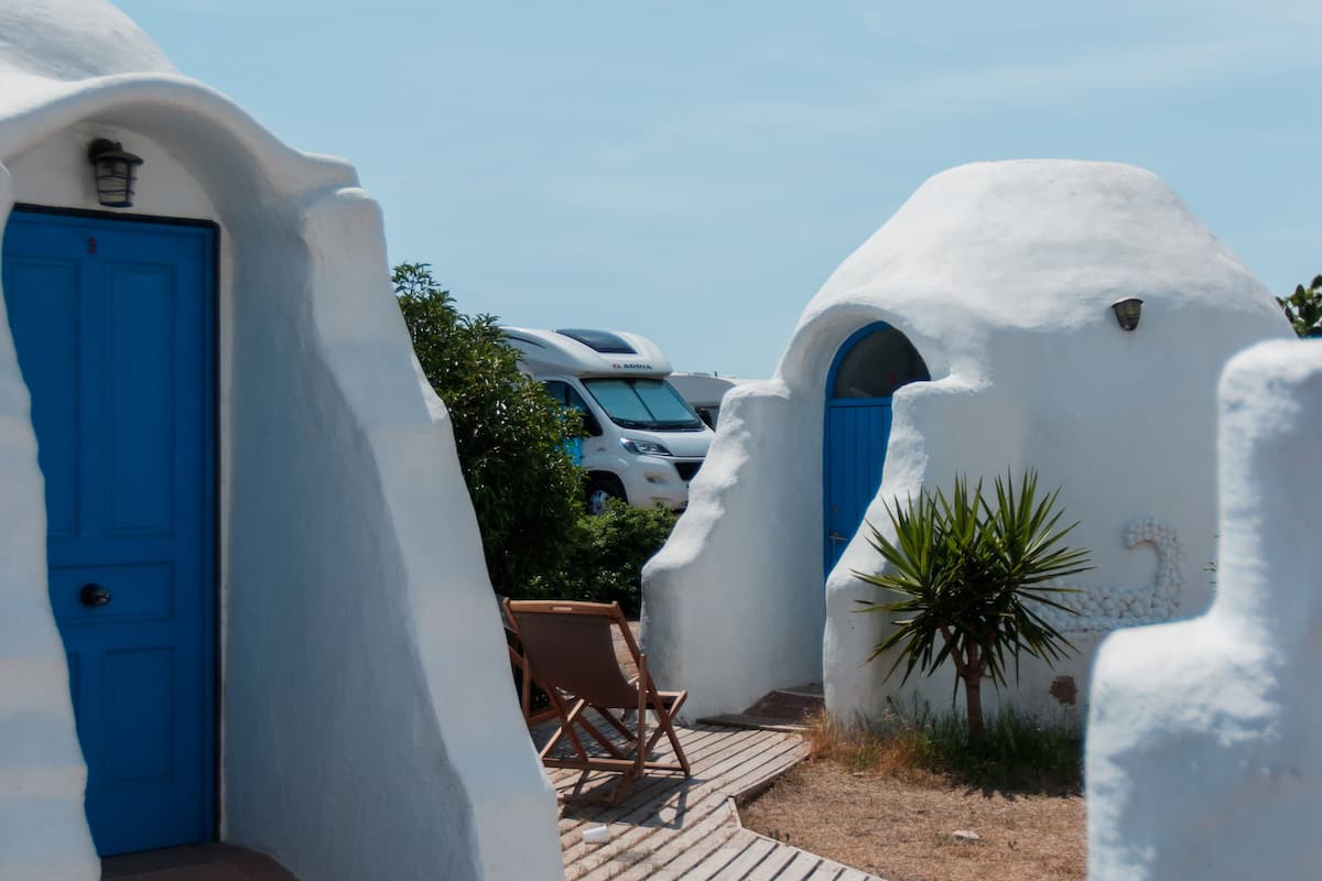 Um edifício branco com porta azul e deck de madeira.