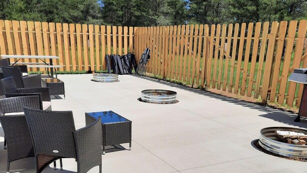 An outdoor patio area with wicker furniture, a round table, and a fire pit. - Model Towne Inn (Gwinn)
